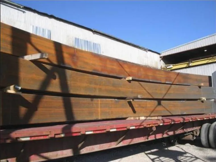 A long bent structural section strapped to a flatbed trailer