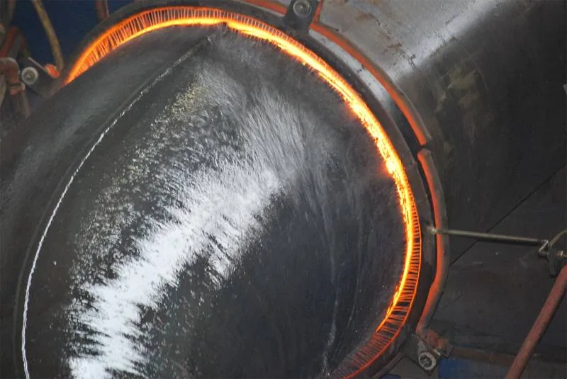Close-up of the glowing induction heat band travelling around a large-diameter pipe during bending