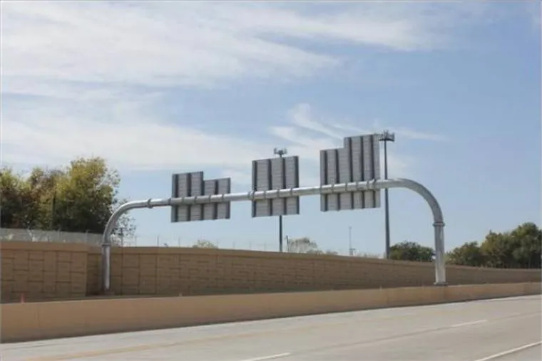 A cantilever highway sign structure of bent pipe carrying overhead signs across a roadway